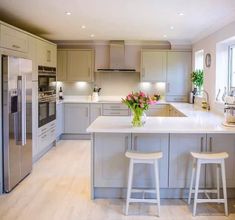 a large kitchen with two stools in front of the counter and an island that has flowers on it