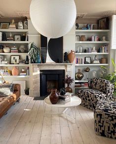 a living room filled with furniture and a fire place under a large white ball hanging from the ceiling