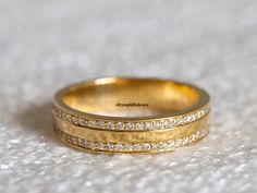 two gold wedding bands sitting on top of a white carpeted floor, with small diamonds in the middle