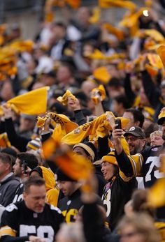 a large group of people wearing yellow and black uniforms, some holding up their cell phones