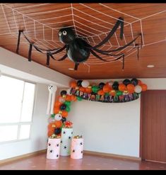 a room decorated for halloween with balloons and decorations on the ceiling, spider net hanging from the ceiling