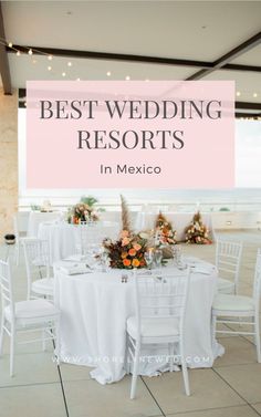 a table set up with white chairs and flowers in the center for a wedding reception