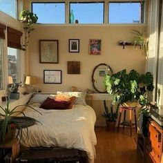 a bed sitting in a bedroom next to a window with lots of plants on it