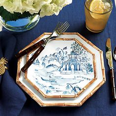 a blue and white table setting with flowers, silverware, and utensils