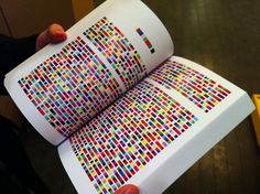 a person holding an open book with colorful squares on it