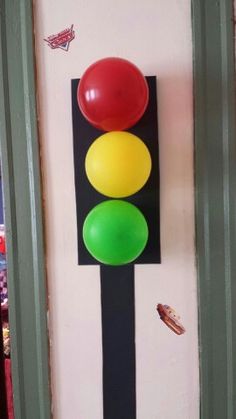 a traffic light mounted to the side of a wall next to a green and red balloon