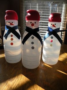 three snowmen made out of plastic bottles sitting on a table