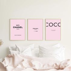 three pink posters are hanging on the wall above a bed with white sheets and pillows