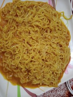 a plate full of noodles and sauce on a colorful tablecloth with other plates in the background