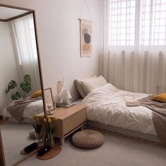 a bedroom with a bed, mirror and plant on the floor in front of it