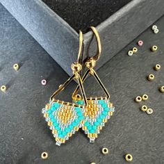 You can choose between silver color (silver plated brass) or gold (gold plated brass) triangular hoop link of size 12mm and earring hook of size . Color: Gold, turquoise, light sea foam Miyuki DB  These earrings epitomize craftsmanship, utilizing top-tier branded beads such as Miyuki Delica beads and TOHO seed beads. Meticulously handcrafted with a robust beading thread, these earrings guarantee enduring shape retention and bead stability, even with continuous wear. A diverse spectrum of color combinations is available to cater to individual preferences, while all metallic components are expertly fashioned from high-quality brass. Hypoallergenic earring hooks prioritize wearer comfort and safety. Each design in the shop reflects a profound commitment to artistry, characterized by painstaki Handmade Geometric Gold Earrings, Gold Beaded Geometric Earrings, Geometric Beaded Gold Earrings, Gold Geometric Beaded Earrings As A Gift, Gold Geometric Beaded Earrings For Gift, Gold Geometric Beaded Earrings, Geometric Gold Beaded Earrings, Handmade Minimalist Triangle Earrings, Minimalist Handmade Triangle Earrings