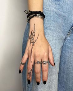 a woman's hand with tattoos and rings on her left wrist, wearing a black bracelet