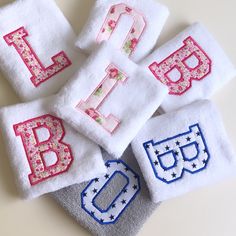 four towels with embroidered letters on them sitting next to each other