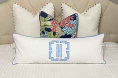 a bed with two pillows on top of it and a decorative pillow in the middle