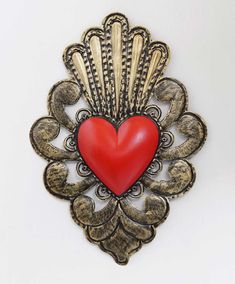 a heart shaped brooch sitting on top of a white wall