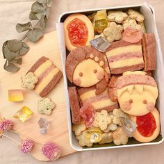 a box filled with lots of food on top of a wooden table next to flowers