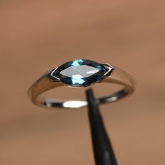 It is a London blue topaz ring. The main stone is 5 mm* 10 mm marquise cut.weight about 1.24 carats. The basic metal is sterling silver and plated with rhodium. To change the metal to a solid gold (white/rose) or platinum is also available, please ask for a quotation if you want. You can also go to my shop Home for more elegant rings: https://www.etsy.com/shop/godjewelry?ref=hdr_shop_menu London blue topaz is November birthstone More London blue topaz rings: https://www.etsy.com/shop/godjewelry? East To West Engagement Ring, Blue Topaz Wedding Ring, London Blue Topaz Engagement Rings, Topaz Wedding Ring, Blue Topaz Engagement Ring, Ring Marquise, Topaz Engagement Ring, London Blue Topaz Ring, Engagement Ring For Women