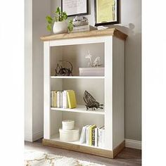 a white book shelf with books and pictures on it in a room next to a wall