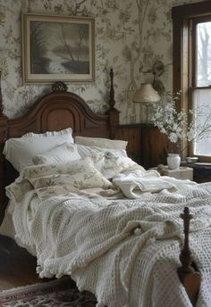 a bed sitting in a bedroom next to a window covered in white blankets and pillows