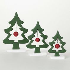 three wooden christmas trees with ornaments hanging from the top one is red and white, while the other two are green