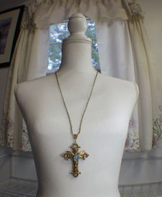 "Vintage inspired ornate floral cross necklace in bronze. A lovely detailed floral cross has been adorned with a delicate bronze dragonfly. Nestled in the center of the dragonfly is a harlequin blue glass opal . The cross and dragonfly have been finished with a clear resin to preserve the beauty of this necklace. Cross is 3 1/2\" in length (includes connector) and 2 1/2\" wide and hangs from a ornate bronze connector. The chain is 28\" bronze plate chain with a 2\" extender chain that fastens wi Vintage Cross Necklace With Antique Finish, Bronze Cross Bohemian Necklace, Bronze Bohemian Cross Necklace, Bohemian Bronze Cross Necklace, Antique Bronze Cross Necklace, Antique Brass Cross Pendant Necklace, Bronze Brass Cross Necklace, Vintage Bronze Crucifix Jewelry, Antique Bronze Crucifix Jewelry