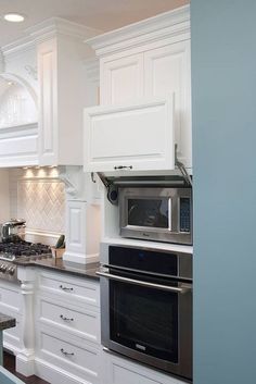 a kitchen with white cabinets and stainless steel stove top oven in the center of the room