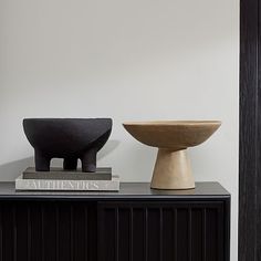 two wooden bowls sitting on top of a black cabinet next to each other in a room