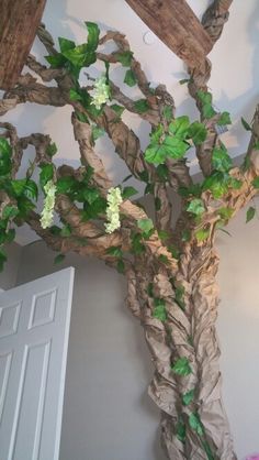 a fake tree with white flowers on it's branches in the corner of a room