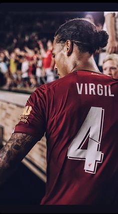 a man wearing a maroon shirt with the number 4 on it is standing in front of a crowd