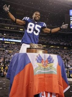 a football player standing on top of a table with his arms in the air and hands raised