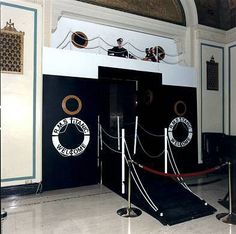 an entrance to a building with ropes and rope barriers around the door, in front of two black doors