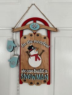 a wooden sign hanging from the side of a white door with snowman on it