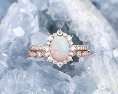 an opal and diamond ring sitting on top of some rocks