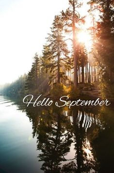 the words hello september are in front of a lake with trees and sun shining on it