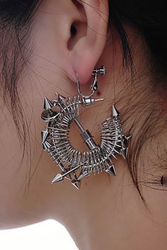 Embrace the perfect fusion of futuristic technology and punk aesthetics with our Temporal Shuttle Earrings. These earrings feature an open circular design, with sections wrapped in spring-like metal, evoking the concept of time travel. Adorned with multiple sharp metal cone accents, they add an edgy and dynamic touch. The central part showcases arrow-like metal elements, enhancing the geometric and innovative design. Crafted from premium materials, these earrings ensure durability and a luxuriou Edgy Metal Hoop Earrings, Edgy Metal Hoop Earrings For Party, Punk Metal Hoop Earrings, Edgy Metal Plug Earrings, Punk Style Metal Hoop Earrings For Party, Edgy Metal Pierced Plug Earrings, Silver Metal Punk Hoop Earrings, Punk Silver Metal Hoop Earrings, Silver Punk Hoop Earrings For Party