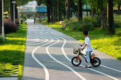 a young boy riding a small bike down a curvy road in the park