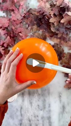 a woman holding an orange frisbee in front of her face with a white stick sticking out of it