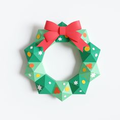 an origami christmas wreath with a red bow on the front and green background