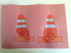 two children's handprints on pink paper with orange and white cones over them