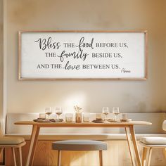 a dining room table with two chairs and a sign above it that says, mess the food before us, the family beside us, and the love between us