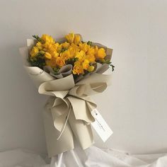 a bouquet of yellow flowers wrapped in white paper