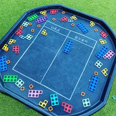 a blue tray filled with colorful dices on top of a grass covered field next to a tennis court