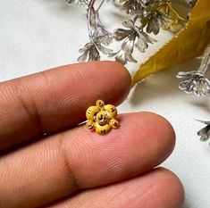 a hand holding a tiny yellow flower ring