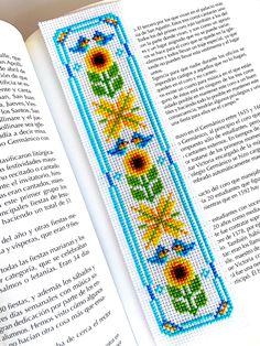 an open book with a cross stitch pattern on the front and back cover, featuring sunflowers