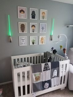 a baby's crib with star wars prints on the wall and pictures above it