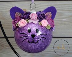 a purple cat ornament with pink roses on it's head and ears