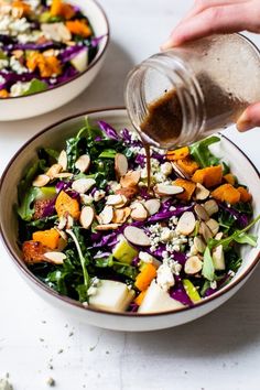 someone pouring dressing onto a salad in a bowl