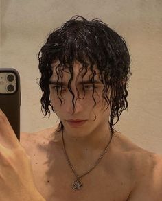 a shirtless man taking a selfie in front of his cell phone with wet hair