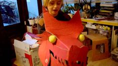 a young boy is playing with a cardboard monster