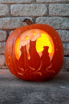 a carved pumpkin with cats on it sitting in front of a brick wall and moon